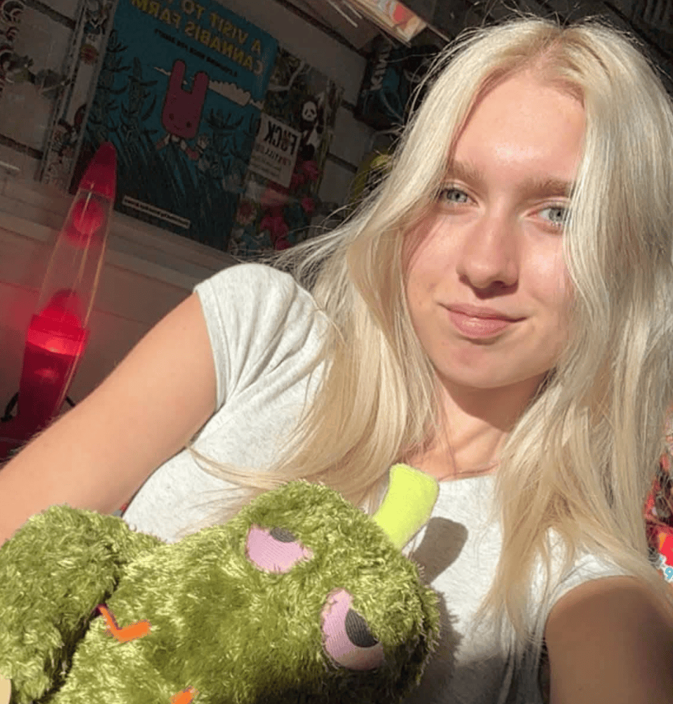 Liv, an associate at Paradise for Adults in Centralia, WA, smiling while posing indoors with a green Fuggler plush toy.