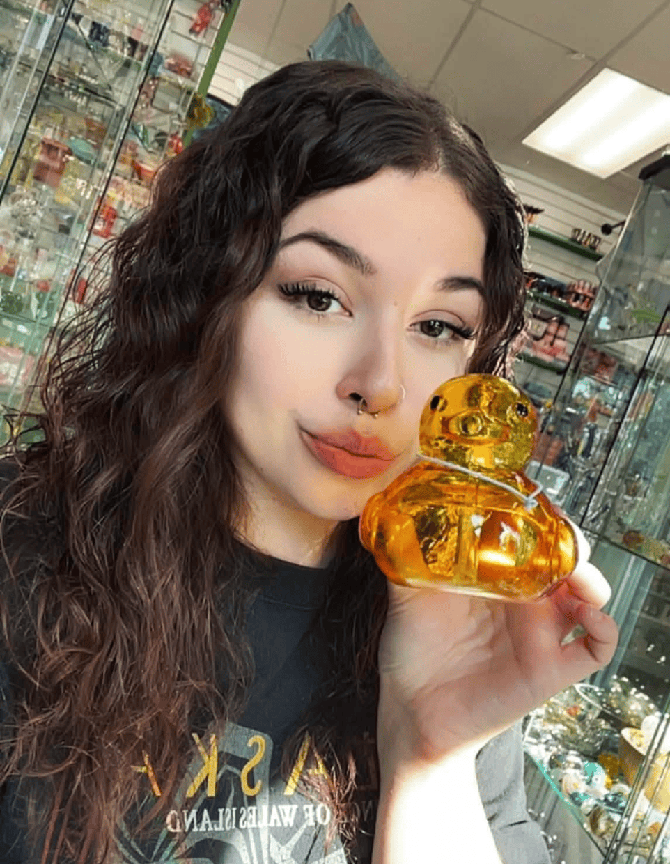 Adriana, an employee at Paradies for Adults in Centralia, WA, holds a yellow amber-colored glass bird.